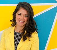 a young professional woman in a yellow blazer standing in front of a blue and yellow background